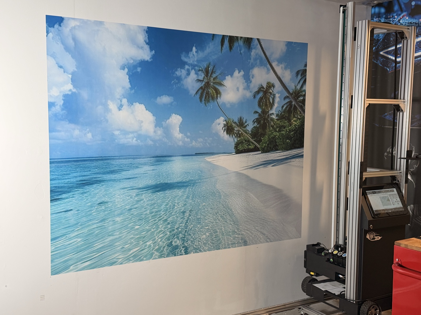 Tropical beach mural on a white wall with the wall-printing machine beside it
